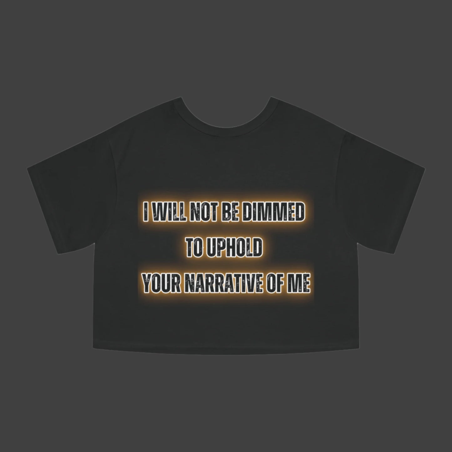 Black t-shirt with text 'I WILL NOT BE DIMMED TO UPHOLD YOUR NARRATIVE OF ME' on a white background