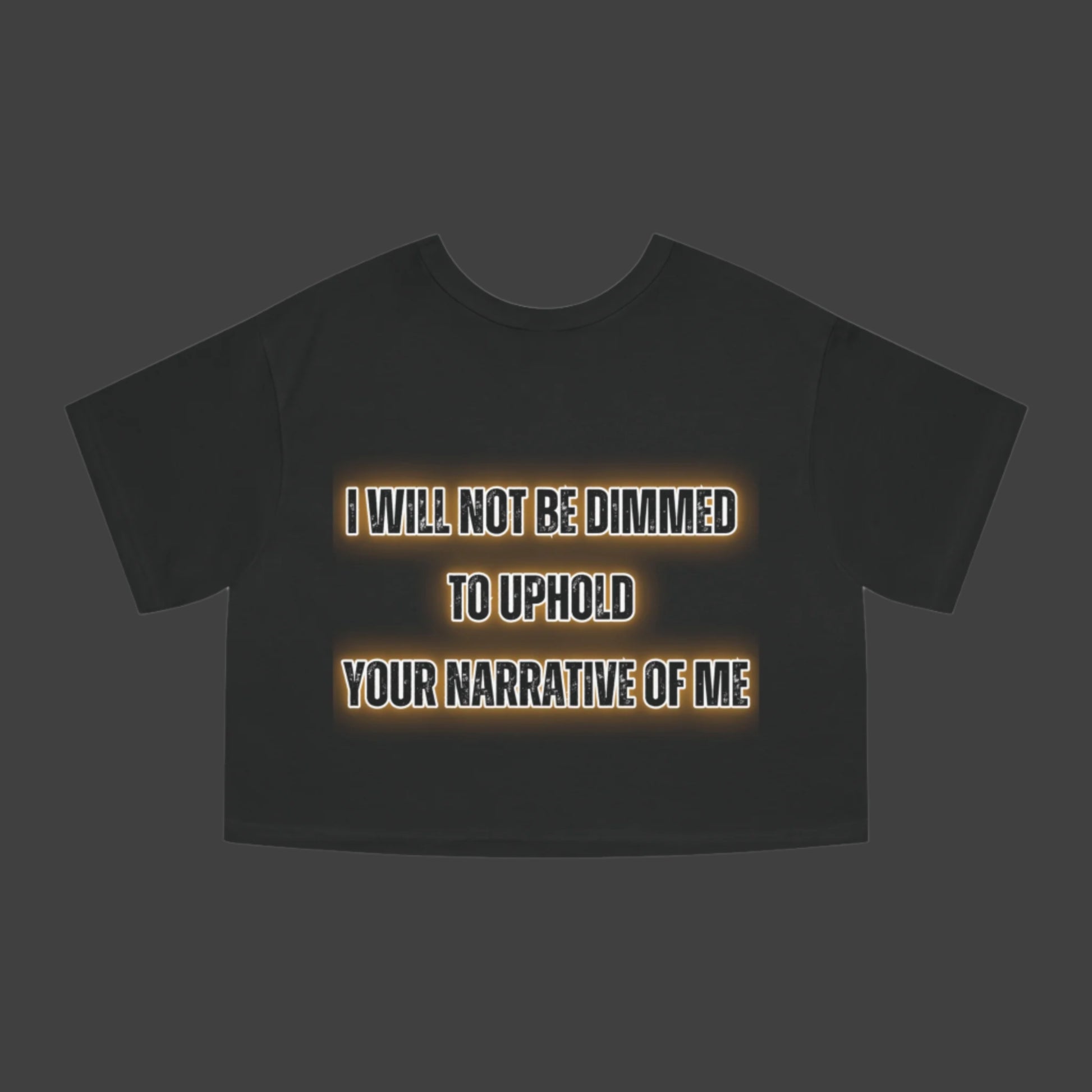 Black t-shirt with text 'I WILL NOT BE DIMMED TO UPHOLD YOUR NARRATIVE OF ME' on a white background